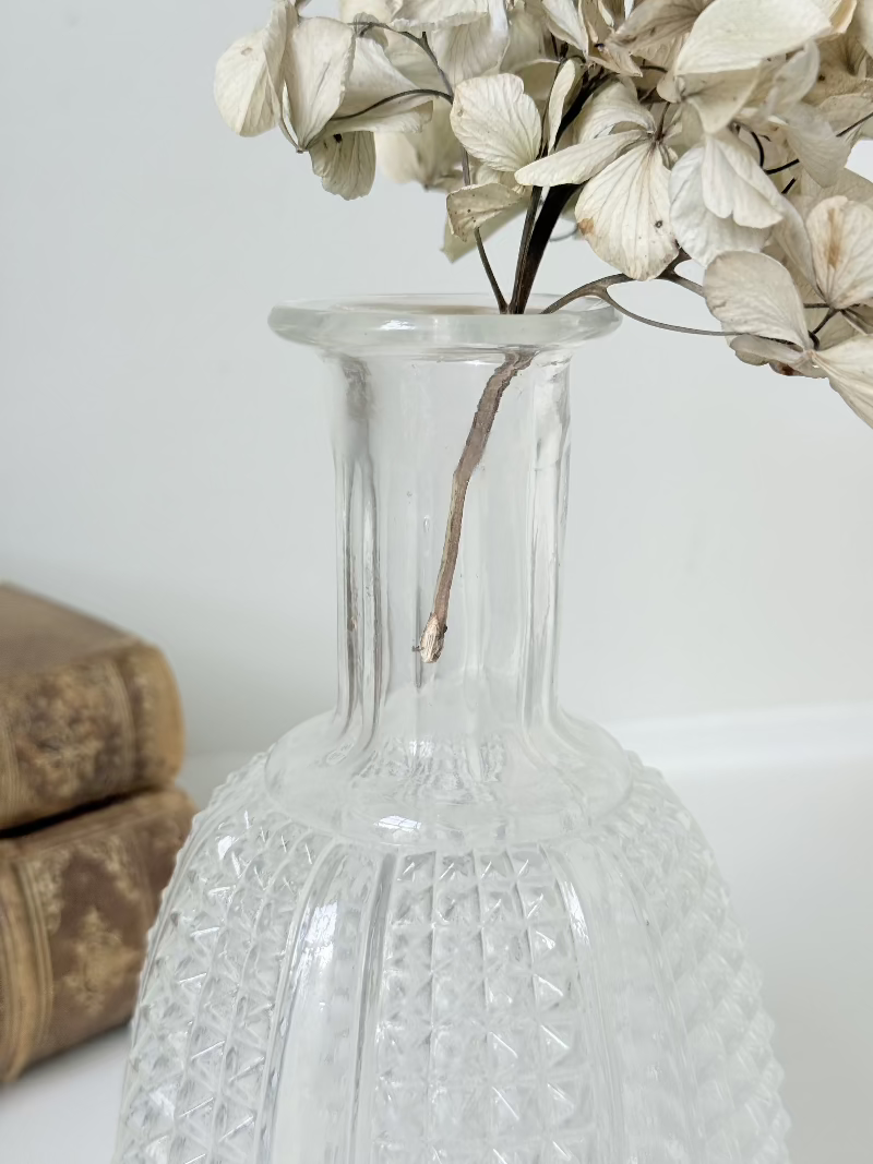 Vintage clear glass vase with textured surface, styled with dried flowers on a white background