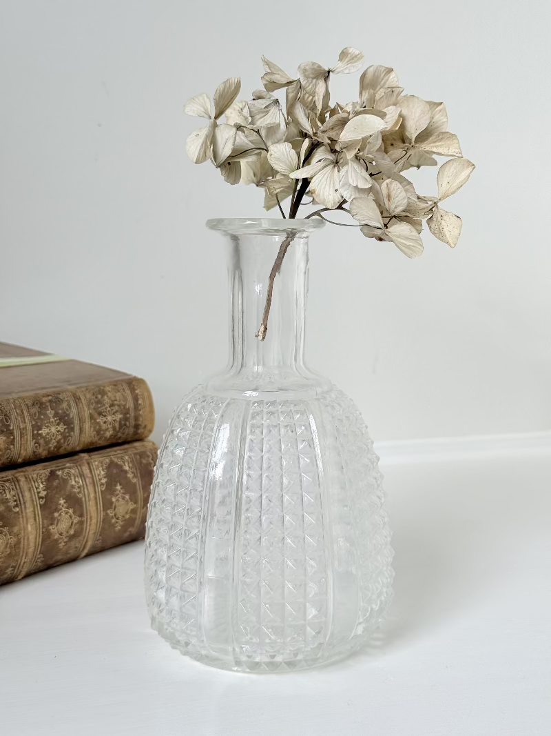 Vintage clear glass vase with textured surface, styled with dried flowers on a white background