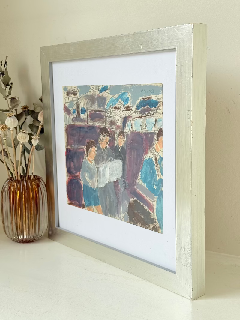 Mixed media painting by Watkiss of figures in a train carriage, framed in white, photographed on a white surface