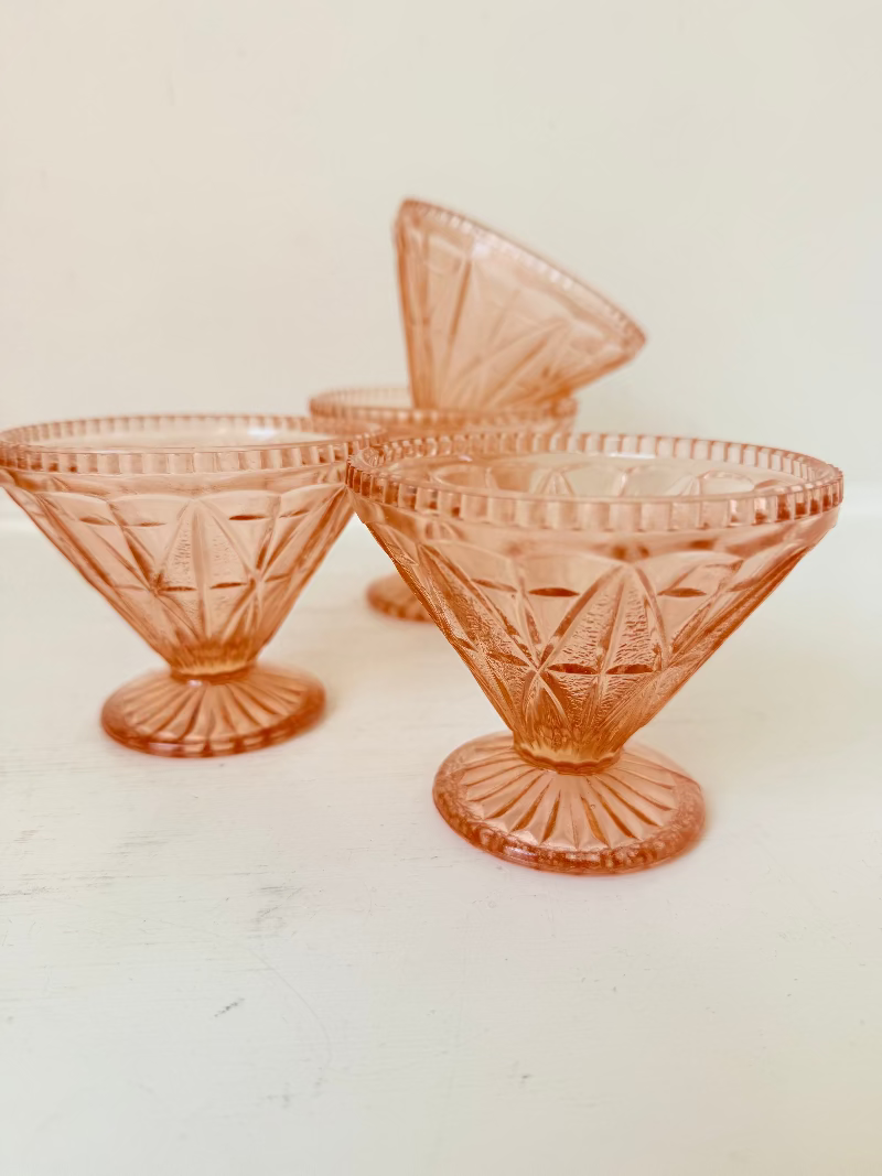 Set of four vintage pressed glass coral dishes with geometric pattern and flared form, photographed on white surface.
