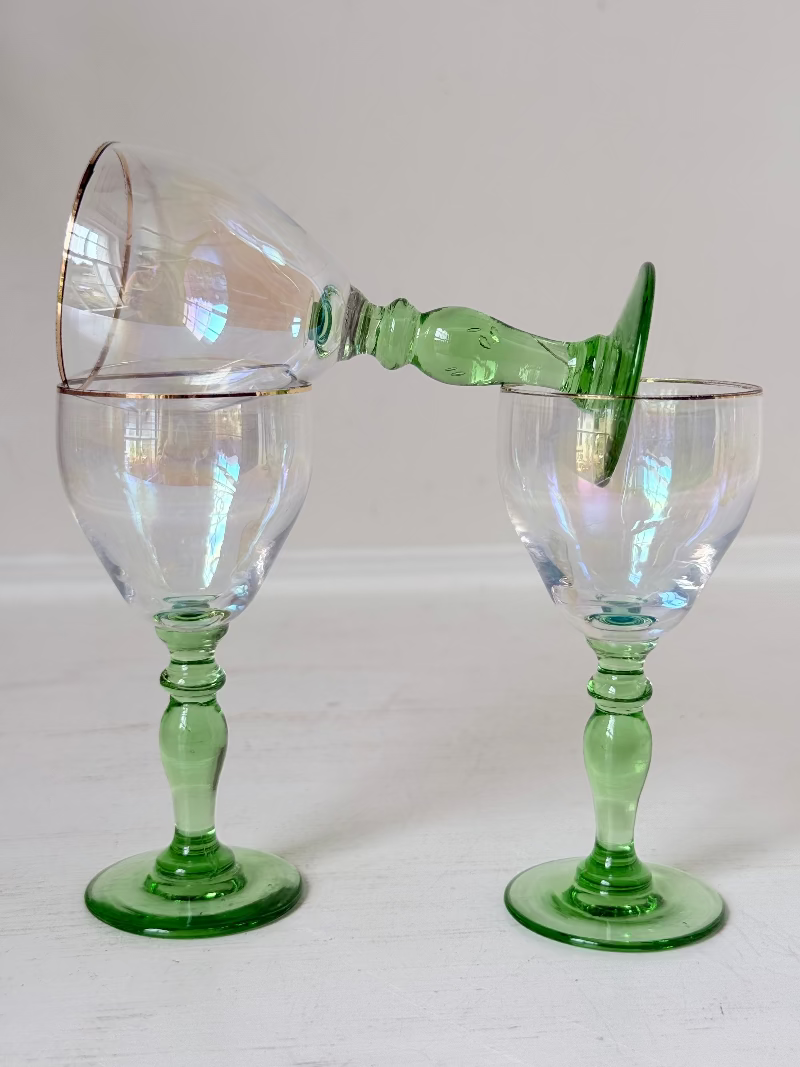 Vintage trio of iridescent shot glasses with green stems and gilt rims, photographed on a white surface