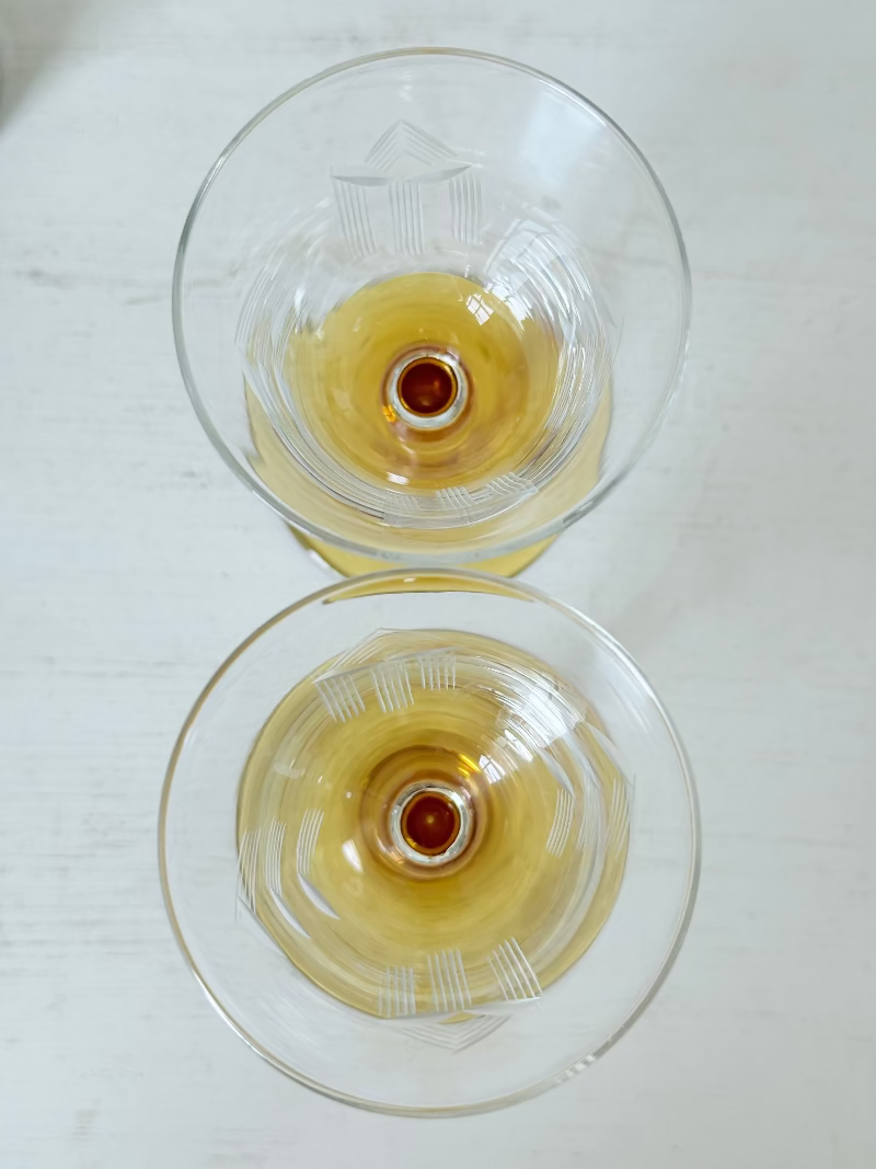Pair of vintage liquor glasses with clear bowls and amber stems, photographed on white surface.