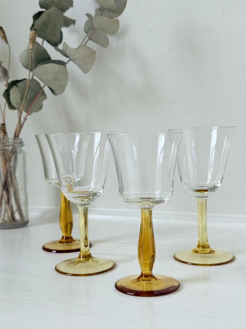 Two pairs of vintage liquor glasses with clear bowls and amber stems, photographed on white surface.