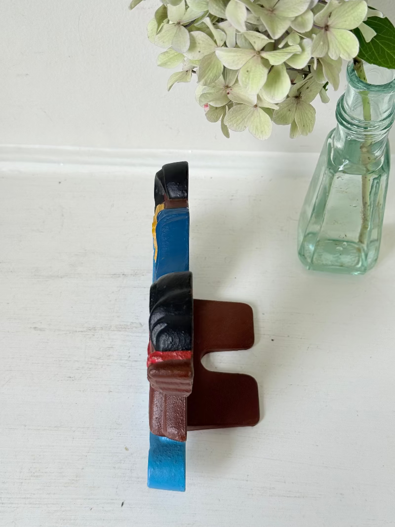 Vintage cast iron rocking horse doorstop with painted finish in red, yellow, blue, and black, photographed on a white surface