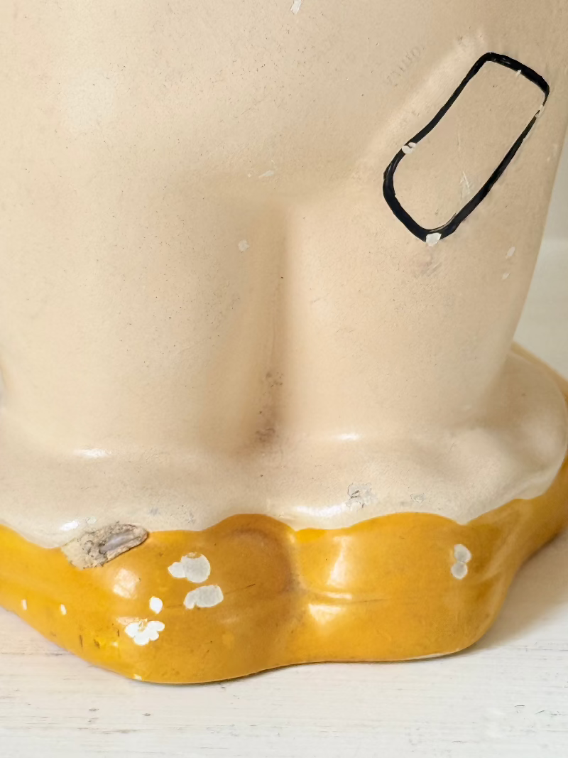 vintage ceramic clown moneybox with green and yellow painted details on white surface