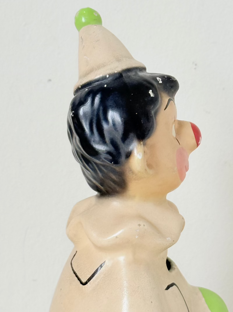 vintage ceramic clown moneybox with green and yellow painted details on white surface
