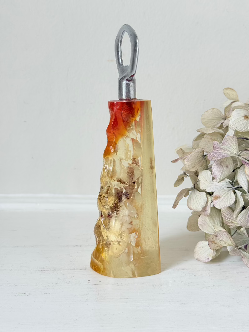 vintage 1970s resin bottle opener with embedded seashells and coastal treasures on white surface