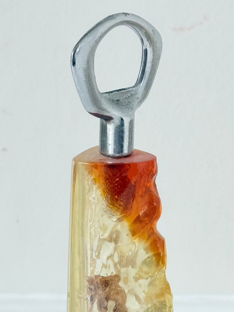 vintage 1970s resin bottle opener with embedded seashells and coastal treasures on white surface