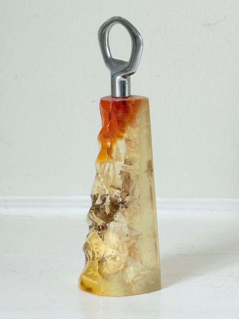 vintage 1970s resin bottle opener with embedded seashells and coastal treasures on white surface