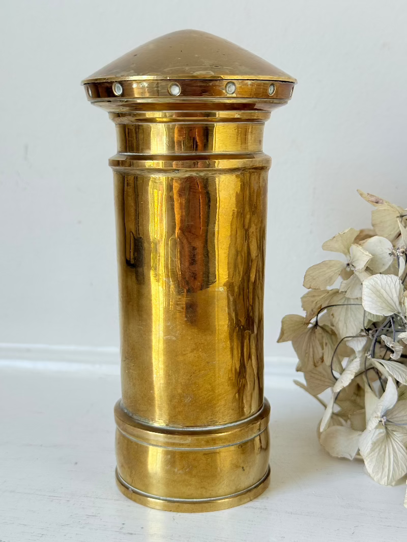 vintage brass post box moneybox with vr emblem photographed on white surface