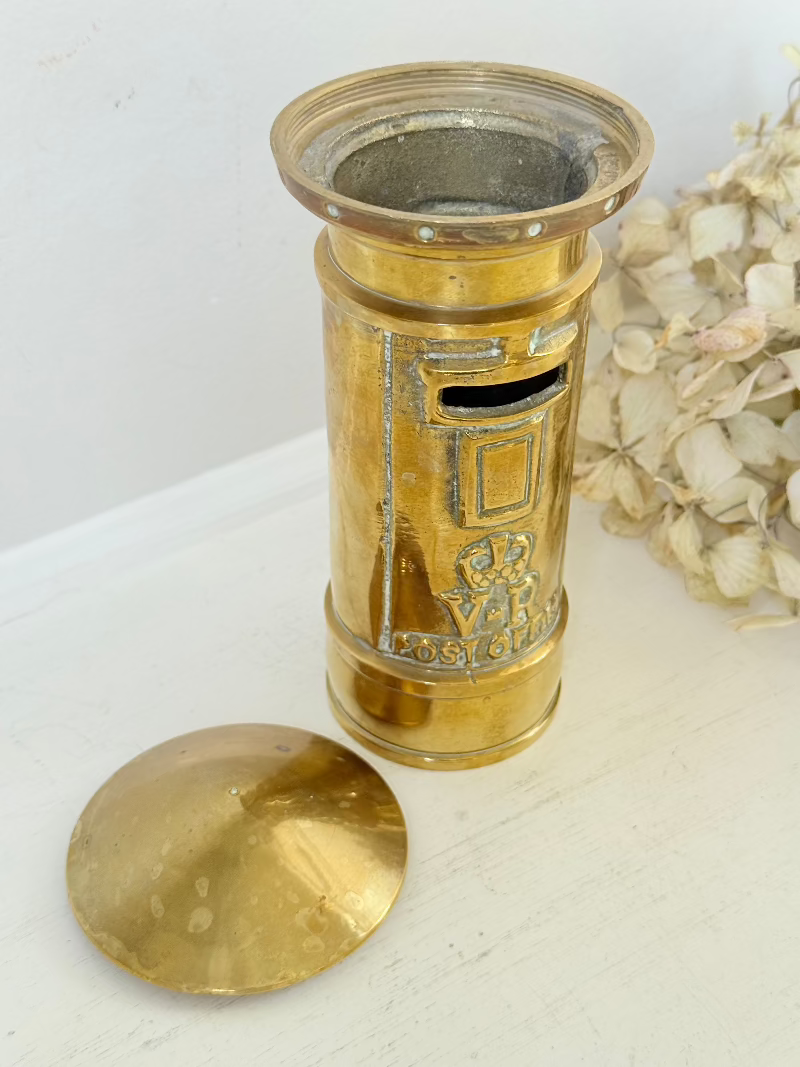vintage brass post box moneybox with vr emblem photographed on white surface