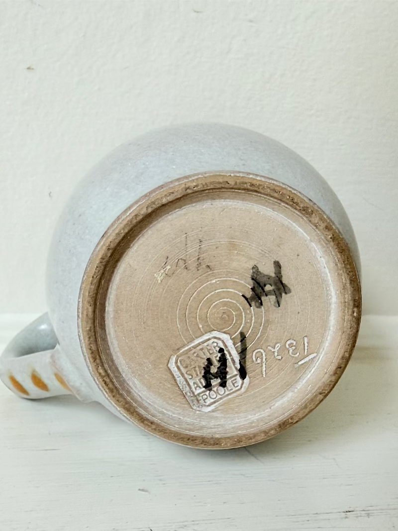 vintage studio pottery milk jug with hand painted lilac flowers and ochre rim photographed on white surface