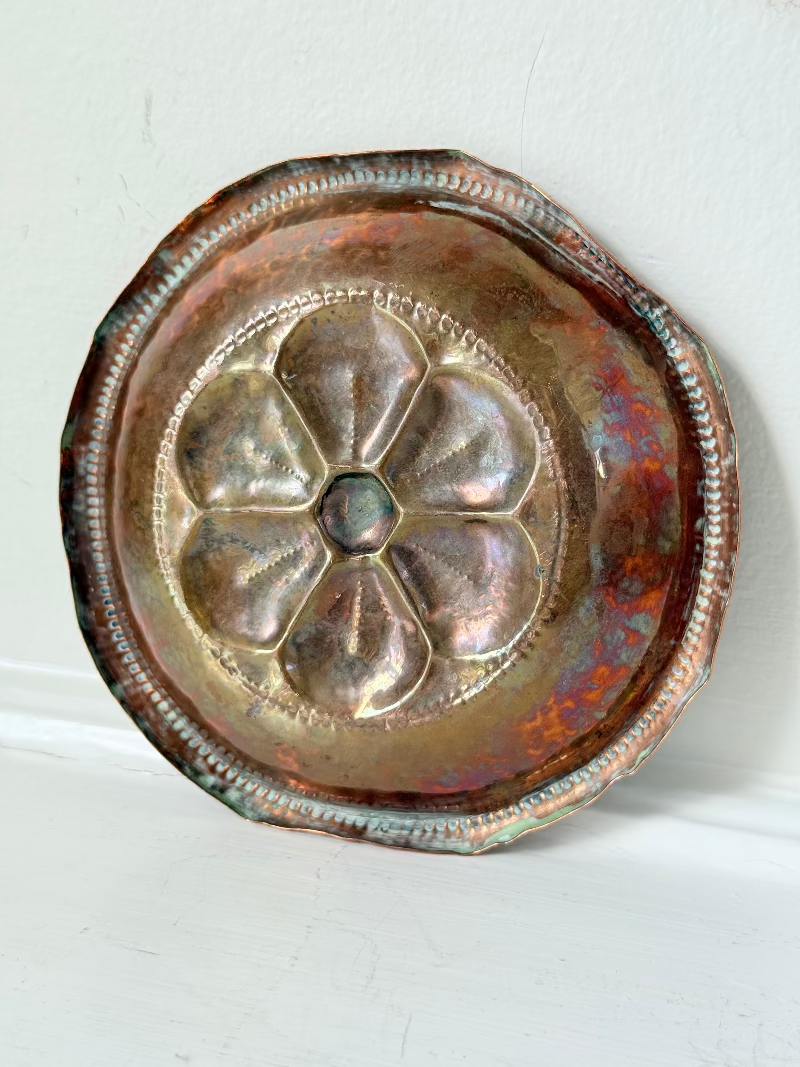 small vintage copper dish with cut-out floral centre photographed on white surface
