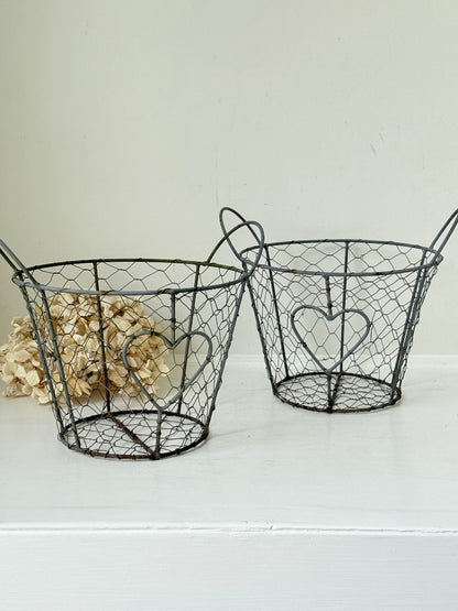 Pair of vintage decorative wire baskets with heart detail and aged patina photographed on a white surface
