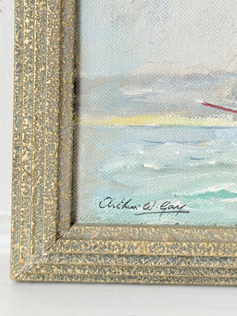 Close-up of a framed painting showing the corner of a seascape with textured gold frame, painted waves, and an artist signature reading Richard W. Gay.
