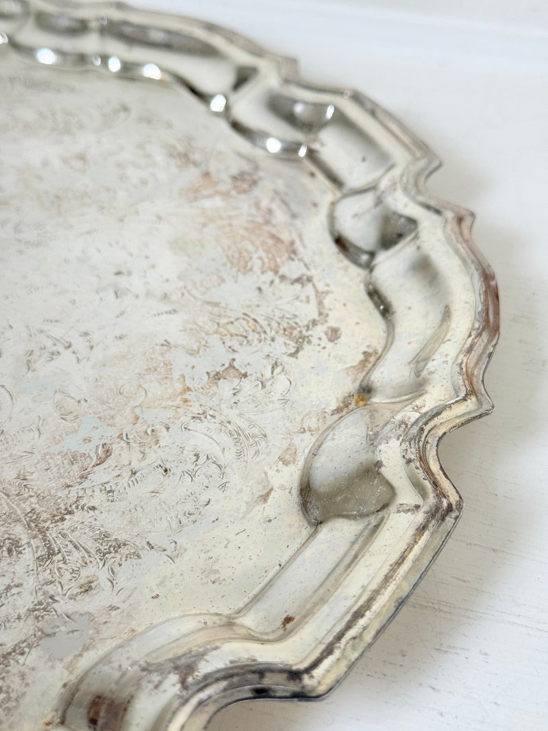 Vintage silver toned round serving tray with piecrust edge, aged patina and decorative scalloped rim for interior styling