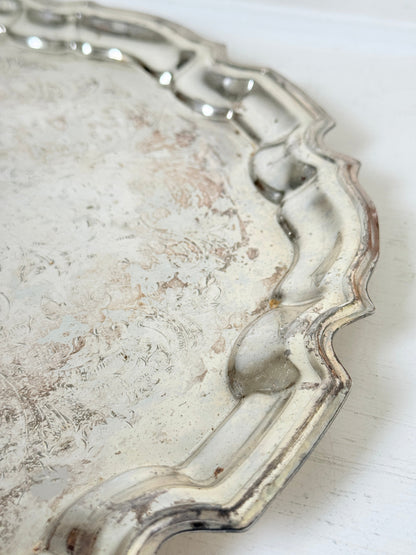 Vintage silver toned round serving tray with piecrust edge, aged patina and decorative scalloped rim for interior styling