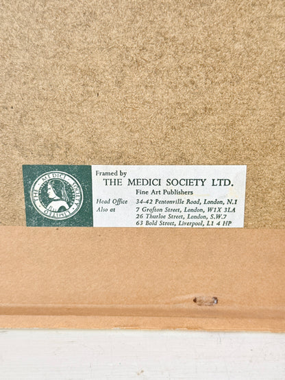 Close-up of the back of a framed art print or painting, showing a brown cardboard backing with a white label that reads &