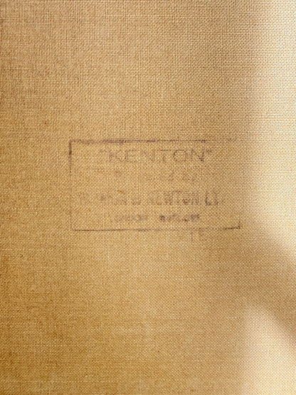 Close-up of a tan woven fabric surface with a faint stamped or printed label reading "KENTON" and smaller text below, plus a soft shadow across the right side.