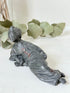 antique japanese bronze reclining lady with impressed marks to base photographed on white surface with foliage background
