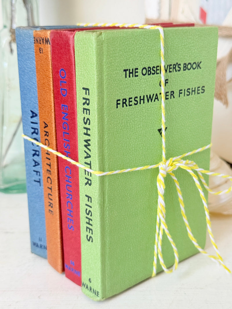 A set of four vintage-style hardcover books tied together with yellow-and-white twine. The front book is light green with black text reading &