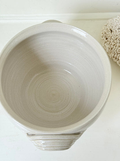 Large studio pottery bowl with hand-painted grape motif and side handles, photographed on a white surface