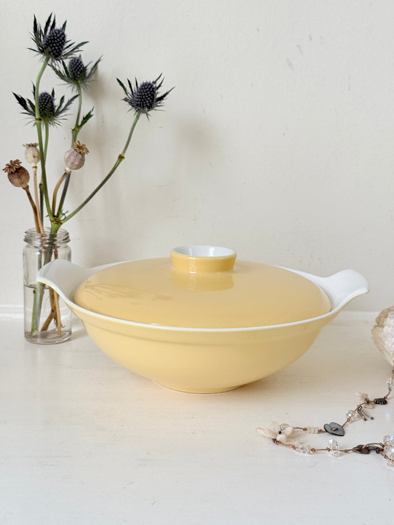 Vintage Poole Pottery lidded serving dish in soft yellow glaze with side handles, photographed on a white surface