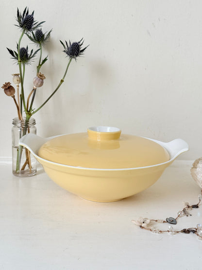 Vintage Poole Pottery lidded serving dish in soft yellow glaze with side handles, photographed on a white surface