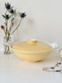 Vintage Poole Pottery lidded serving dish in soft yellow glaze with side handles, photographed on a white surface