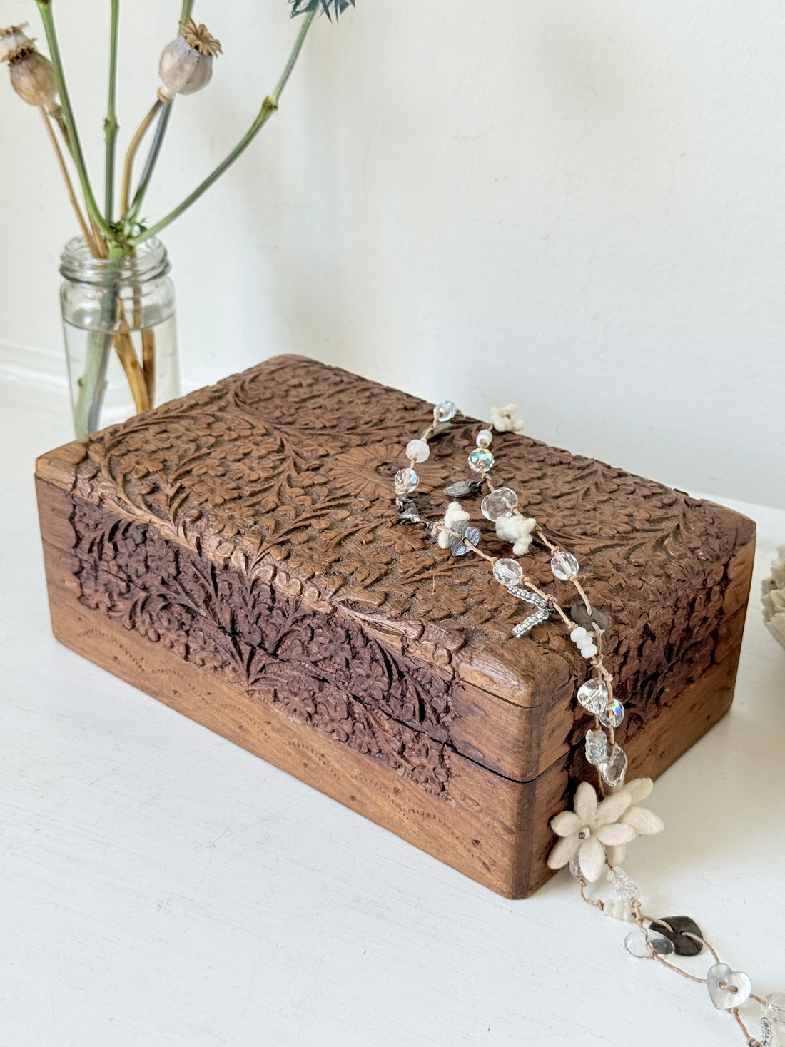 Vintage floral carved wooden jewellery box with detailed hand carved decoration, photographed on a white surface