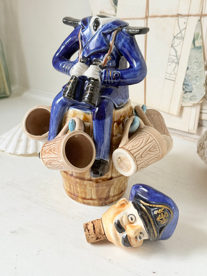 Vintage figural ceramic decanter set with captain, navy blue uniform, barrel base and 6 matching barrel shot cups