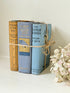 Vintage decorative book bundle in blue and ochre tied with twine, photographed on a white surface