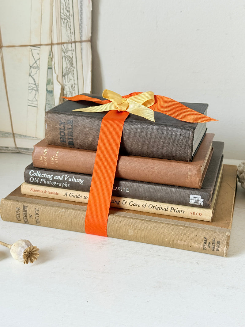 Vintage decorative book bundle in orange and brown with aged hardback covers and bright orange ribbon for shelf styling