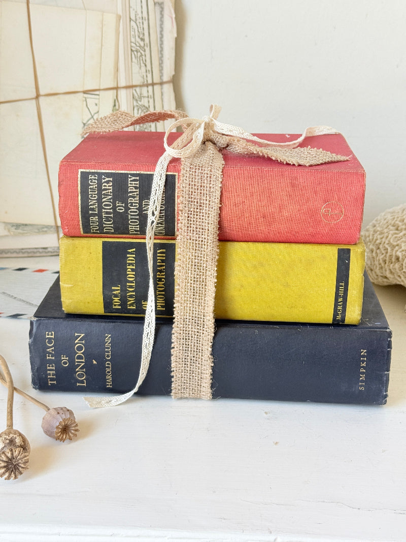 Vintage decorative book bundle in blue yellow and red with aged hardback covers tied with natural ribbon for bookshelf styling