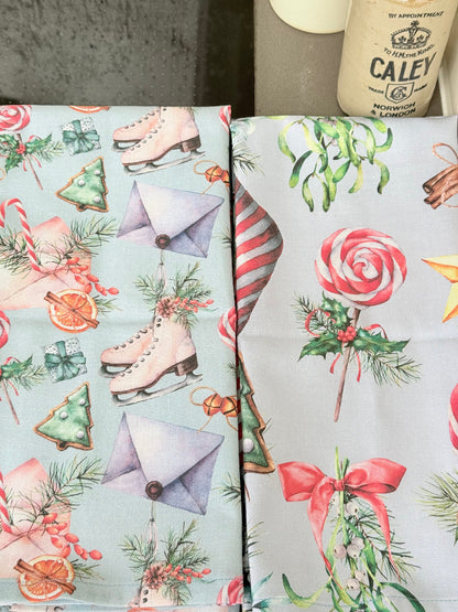 Pair of pastel blue festive tea towels with candy cane and ribbon print, folded, photographed on a kitchen worktop