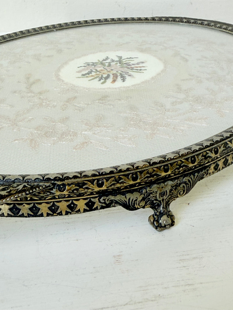 Vintage oval metal tray with pierced gallery sides, twin handles, and floral centre, photographed on white surface.