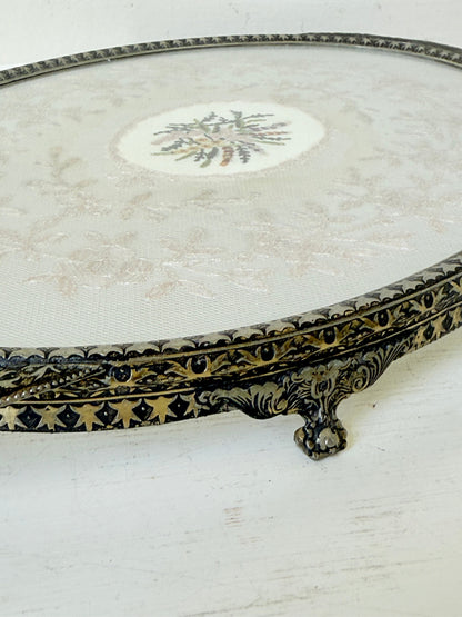 Vintage oval metal tray with pierced gallery sides, twin handles, and floral centre, photographed on white surface.