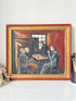 A framed vintage-style oil painting depicting three men sitting around a table in a dimly lit room, with a red and gold frame, displayed on a white surface.