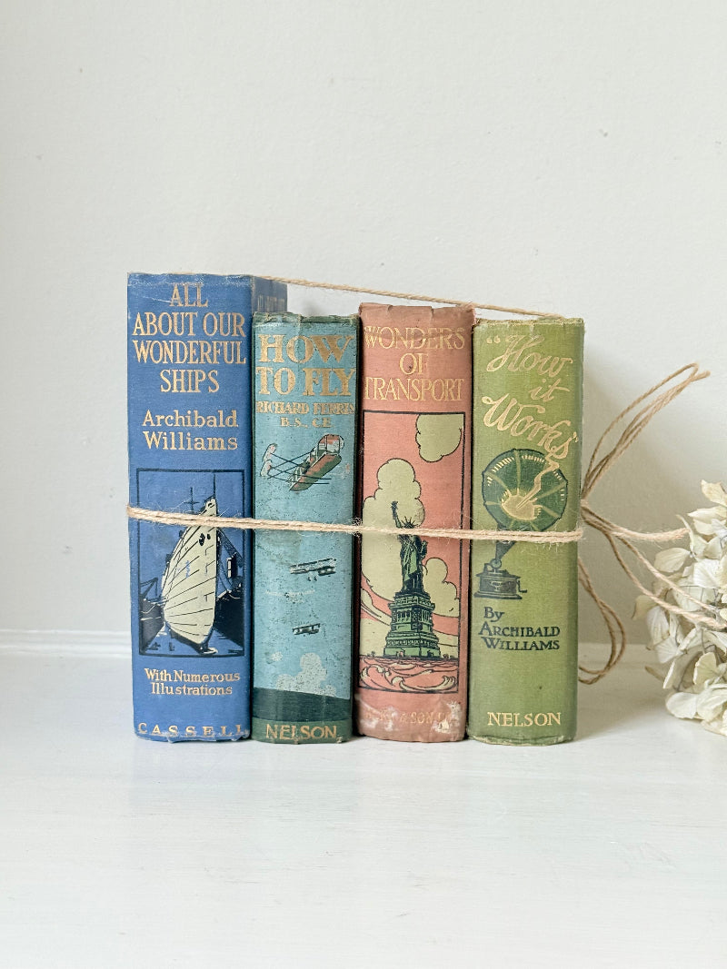 Vintage decorative book bundle in green, blue, and coral with printed lettering, tied with twine, photographed on a white surface