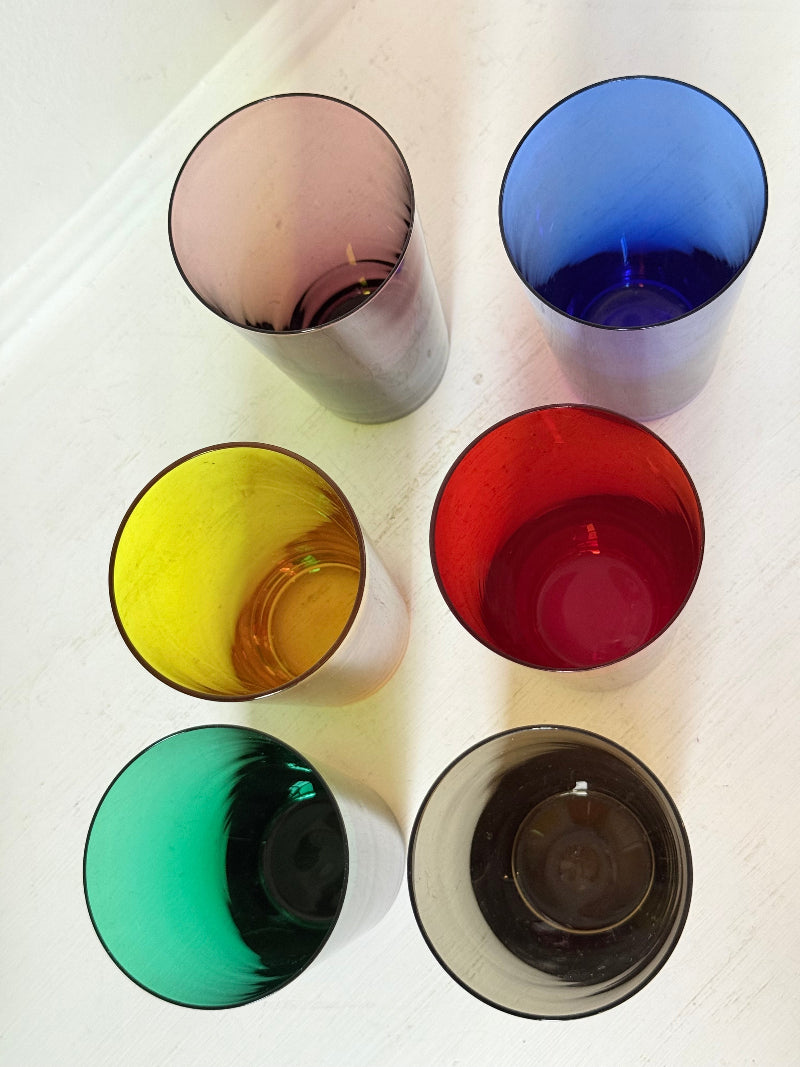 Set of six mid-20th century Boussu coloured glass tumblers in green, yellow, red, violet, blue and brown, photographed on white surface.
