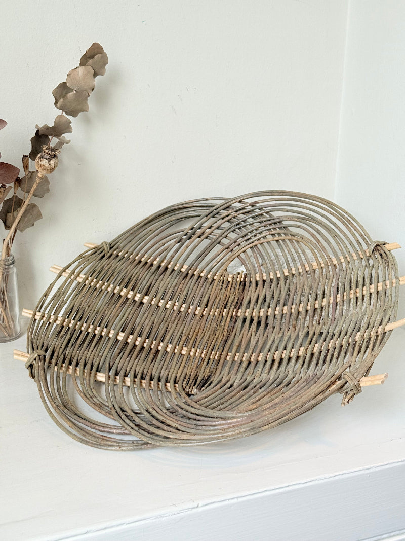 Large vintage loose weave rattan basket tray in grey tone, photographed on a white surface