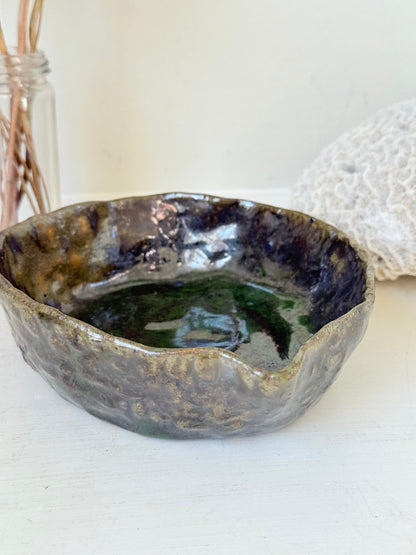 Studio pottery olive bowl with green and charcoal glaze, photographed on a white surface