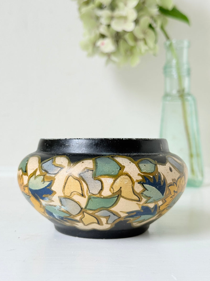 Brentleigh Ware Art Deco pottery jar with hand painted floral decoration on a black ground, photographed on a white surface