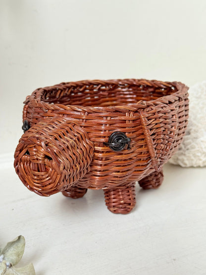 Vintage wicker pig basket planter in warm brown, photographed on a white surface