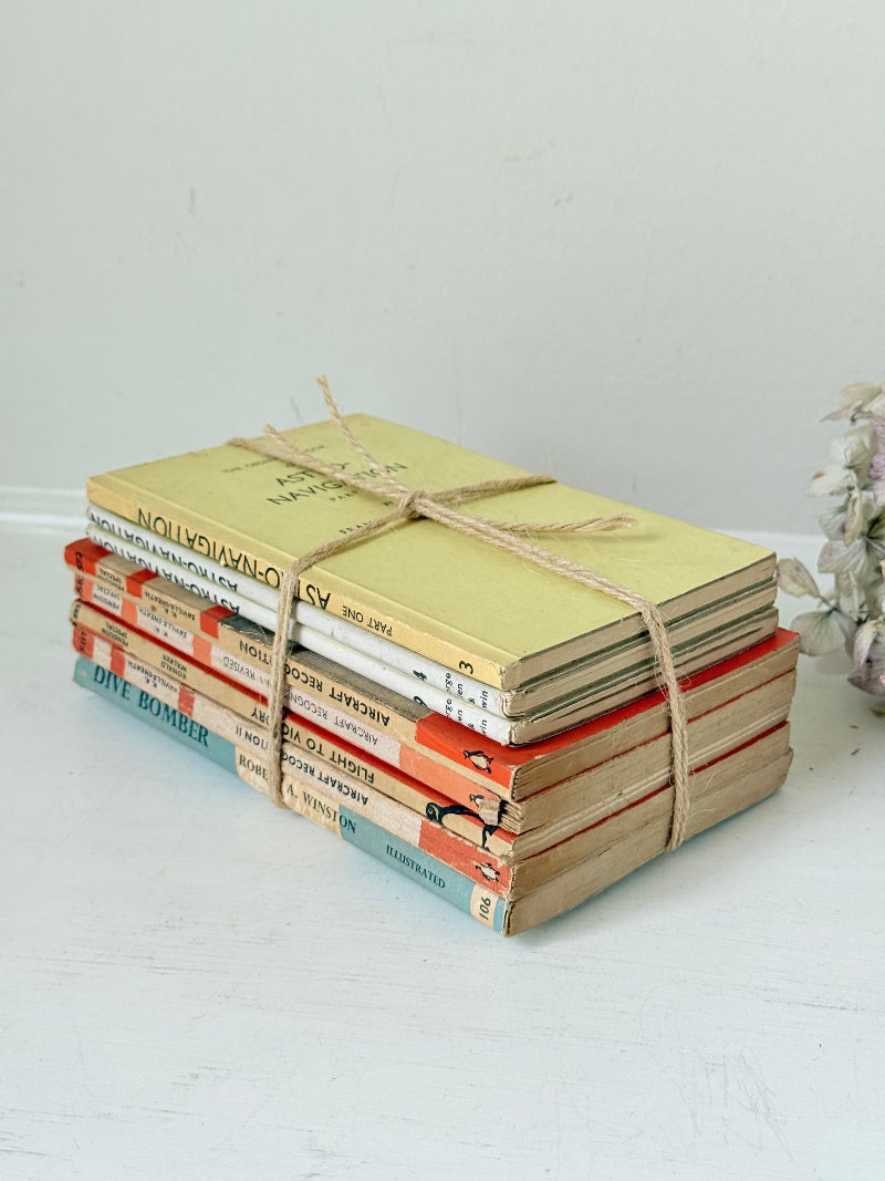 Bundle of vintage Penguin paperback books in orange and cream tones tied with twine, photographed on a white surface