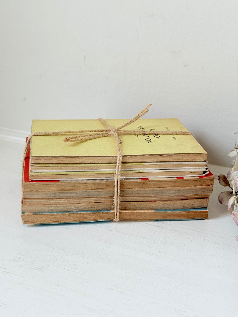 Bundle of vintage Penguin paperback books in orange and cream tones tied with twine, photographed on a white surface
