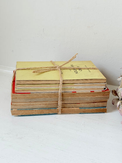 Bundle of vintage Penguin paperback books in orange and cream tones tied with twine, photographed on a white surface