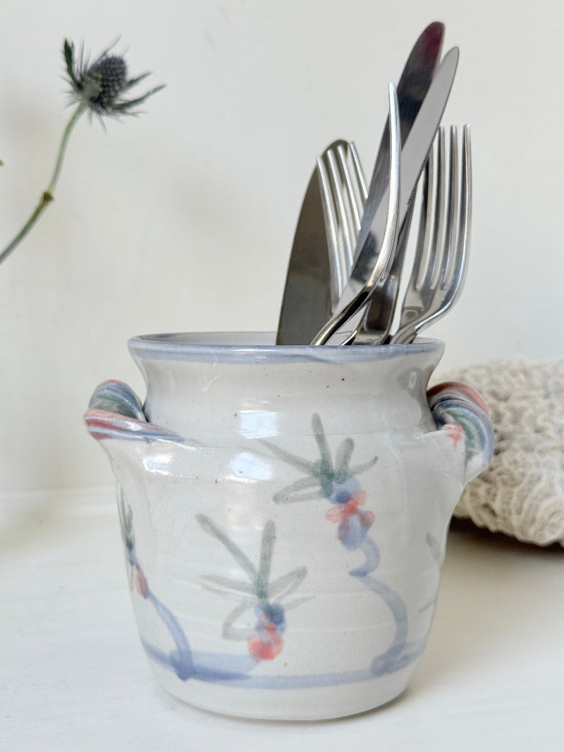 Vintage studio pottery utensil pot with hand painted floral decoration and applied handle detail, photographed on a white surface