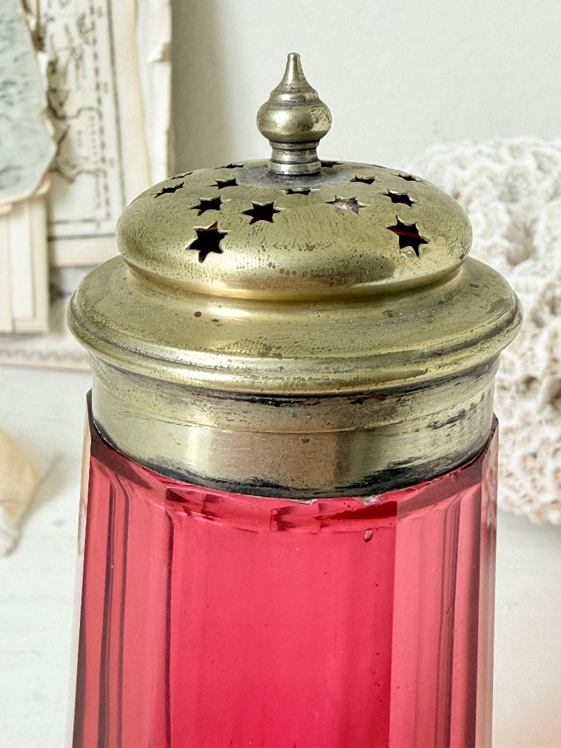 Antique cranberry glass sugar shaker with ribbed optic body, pierced metal top, star holes and deep pink glass