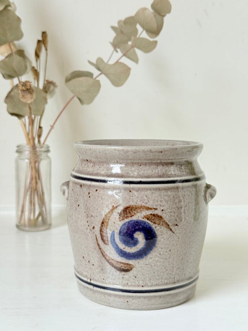 Vintage stoneware confit pot with blue and brown folk art design, photographed on a white surface